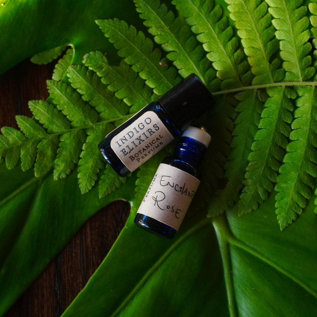 Two sample rollers of Indigo Elixirs Enchanted Bloom on green leaves